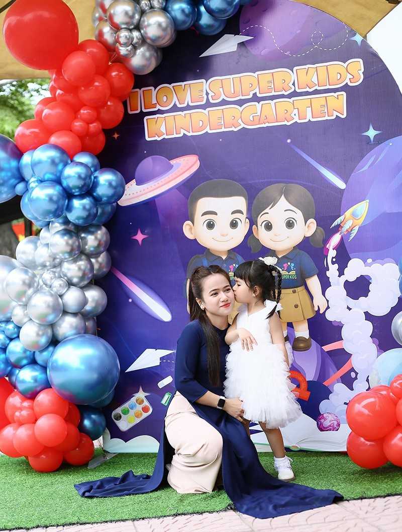 2 người chụp bên backdrop khai giảng màu tím