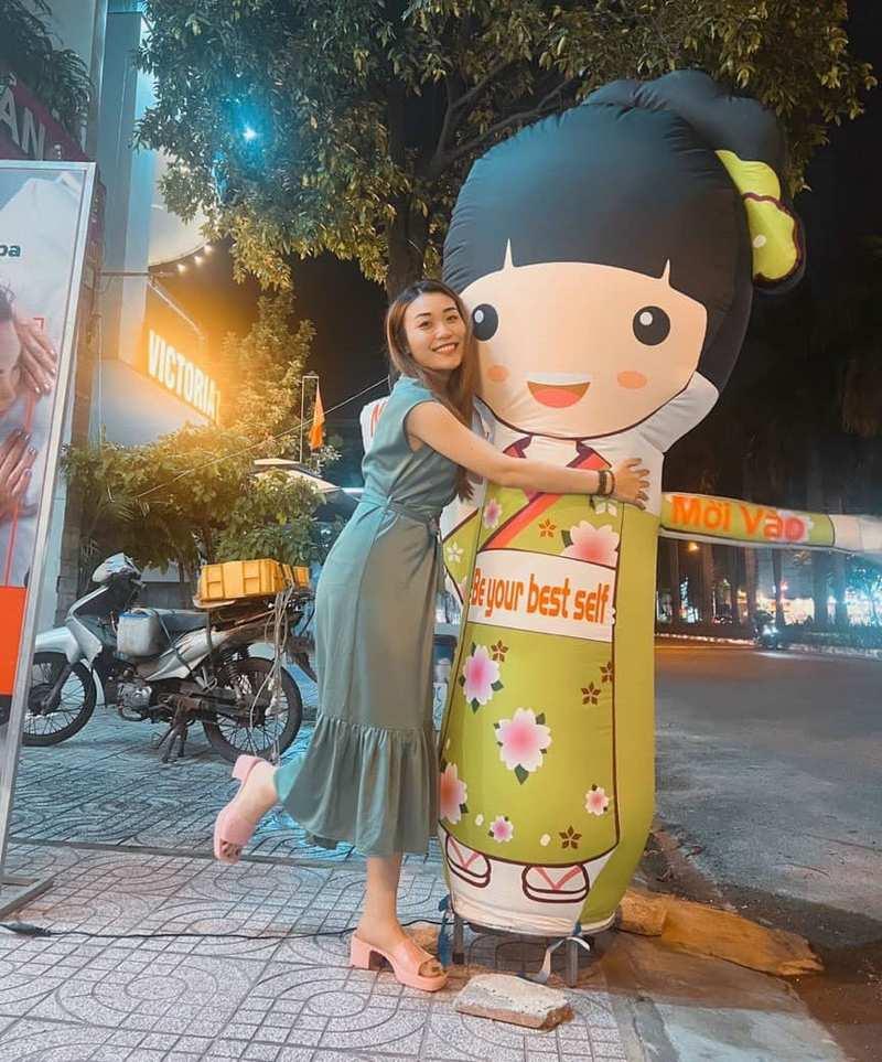 Chị gái ôm rối hơi khai trương hình cô gái mặc áo dài xanh tại dịch vụ cho thuê rối hơi vẫy tay khai trương giá rẻ HCM.