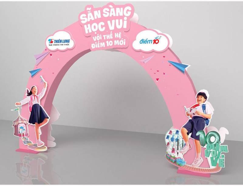 Thi công cổng chào sự kiện booth siêu thị trọn gói với thiết kế màu hồng và hình ảnh học sinh vui vẻ.